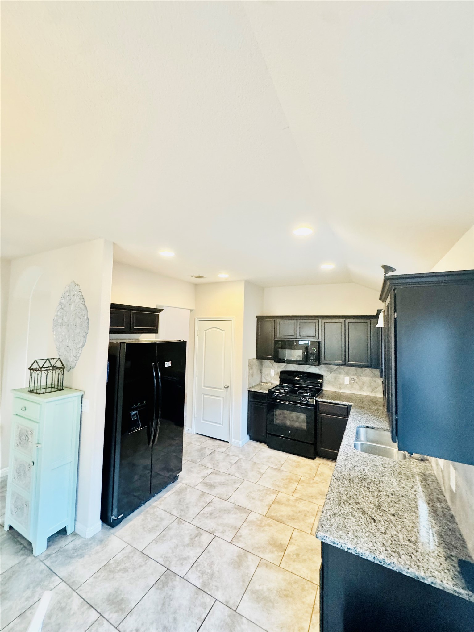 413 Gettysburg Loop Elgin, TX 78621 - Photo 9 of 32 a kitchen with kitchen island granite countertop a refrigerator and a sink