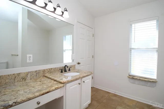 a bathroom with a granite countertop sink and a mirror