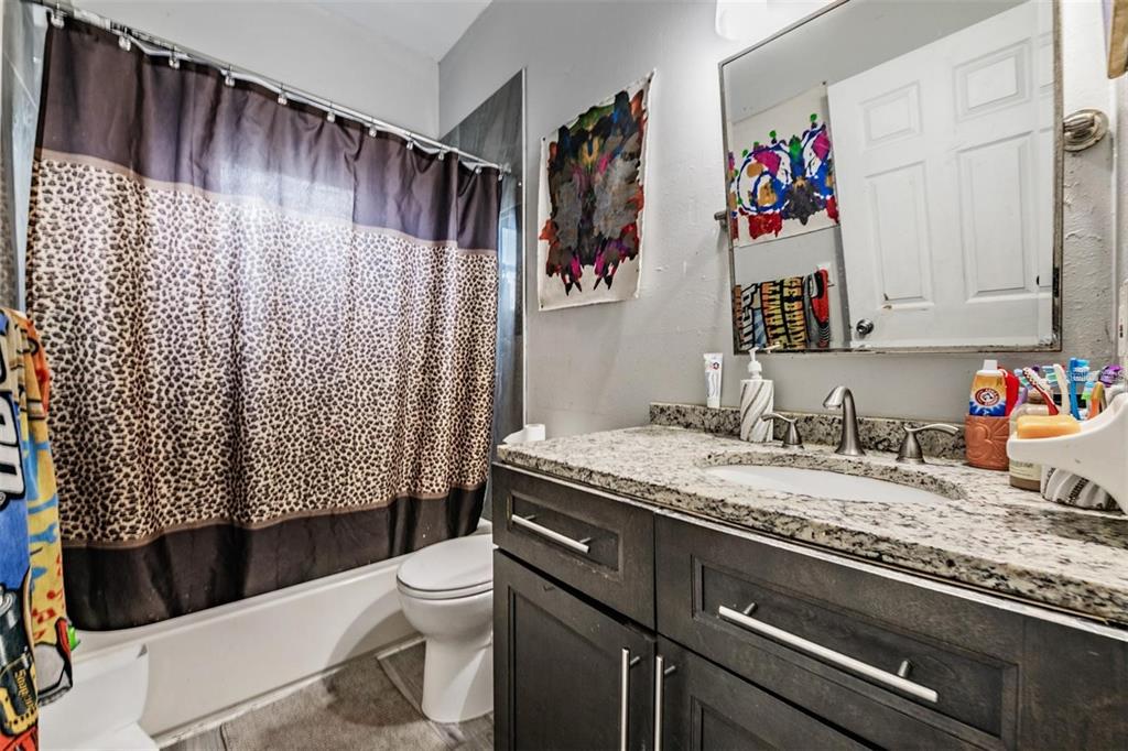 8304 North 13th Street Tampa, FL 33604 - Photo 18 of 22 a bathroom with a granite countertop sink and a toilet