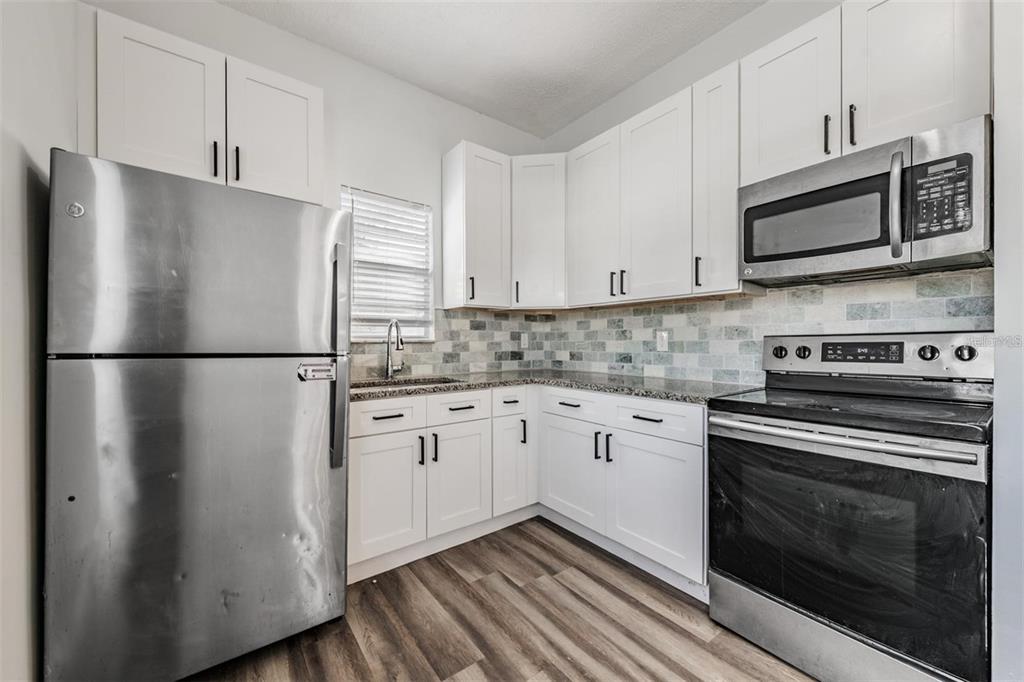 8304 North 13th Street Tampa, FL 33604 - Photo 8 of 22 a kitchen with stainless steel appliances white cabinets white stove a refrigerator and a microwave