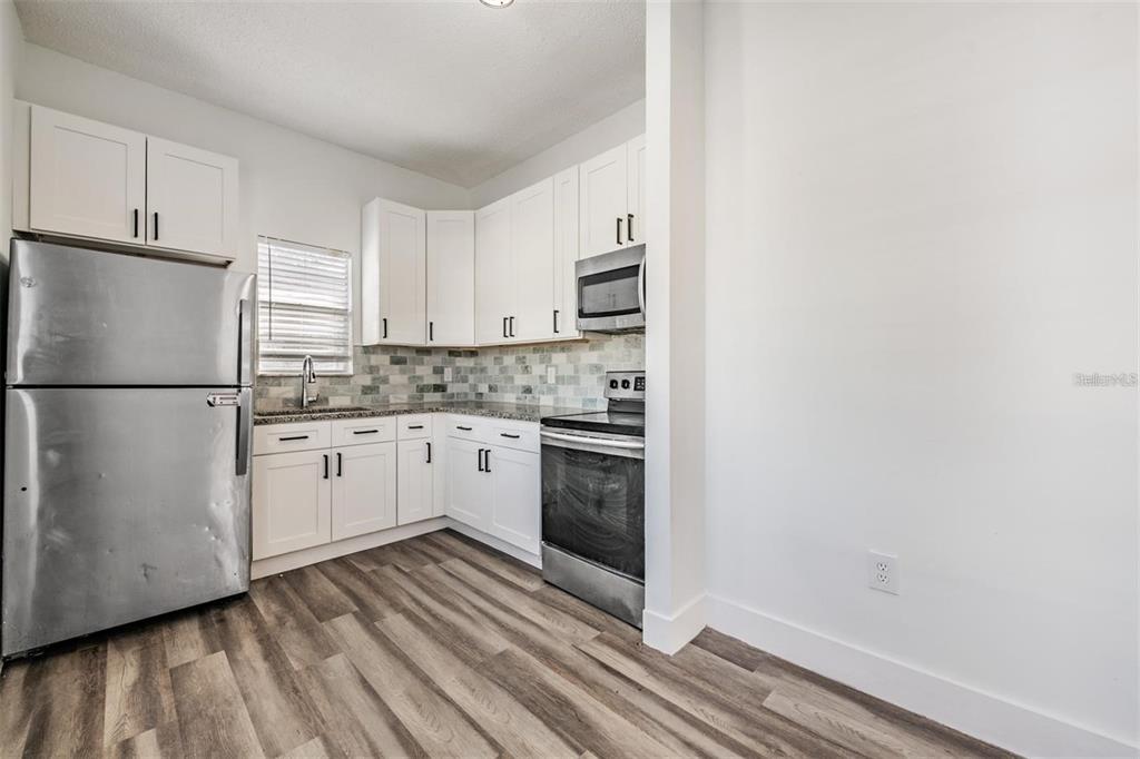 8304 North 13th Street Tampa, FL 33604 - Photo 9 of 22 a kitchen with stainless steel appliances granite countertop a refrigerator sink and white cabinets