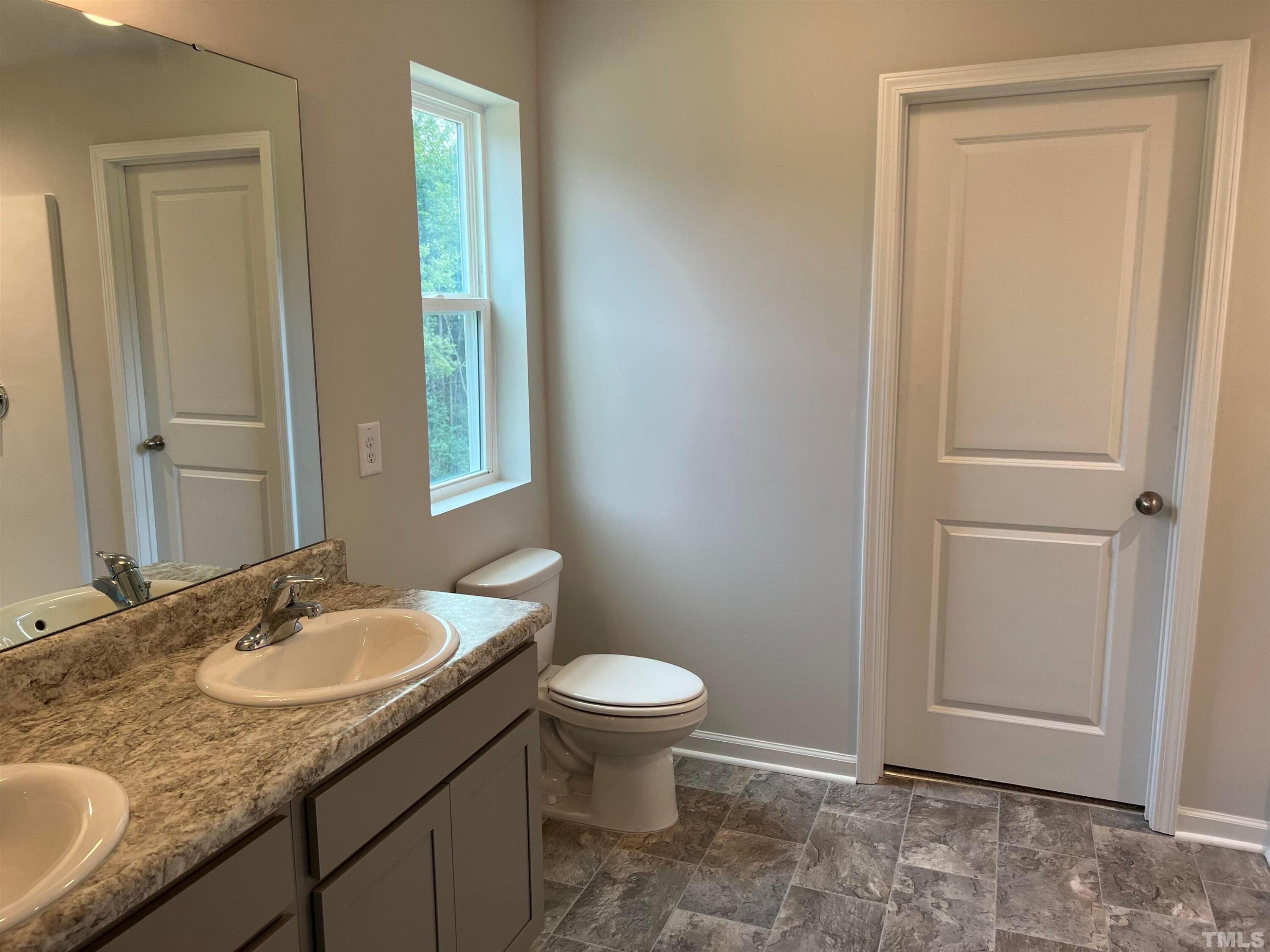 179 Maple Tree Lane Clayton, NC 27527 - Photo 14 of 18 a bathroom with a granite countertop sink a toilet and a mirror