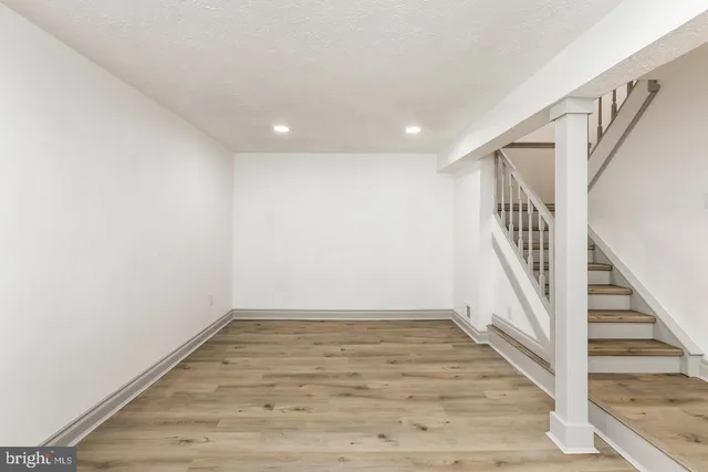 a view of an empty room with wooden floor and stairs