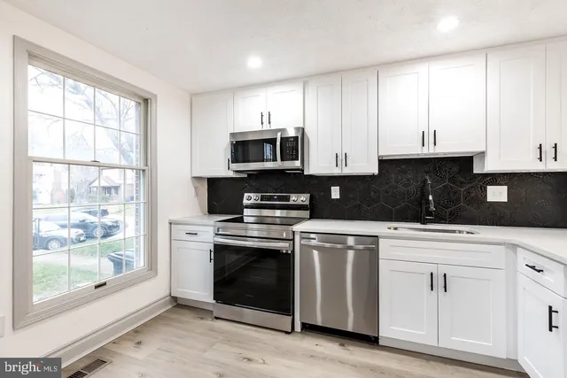 a kitchen with white cabinets and appliances