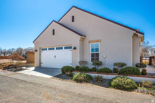 4222 Hampshire Road Hurricane, UT 84737 - Photo 12 of 12 Stucco exterior featuring a pitched roofline, an attached garage with a panel door and window inserts, and sconce lighting