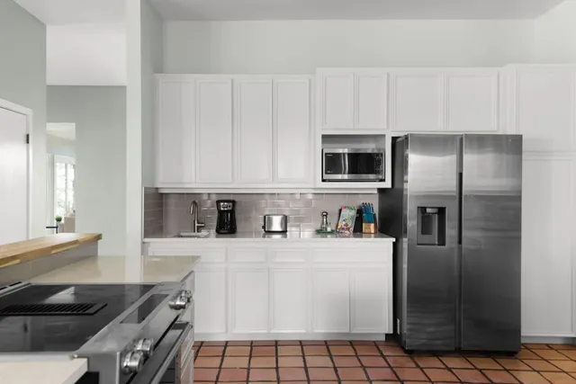 a kitchen with stainless steel appliances a refrigerator sink and white cabinets