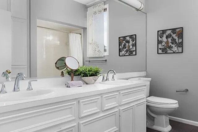 a bathroom with double vanity a toilet a and mirror