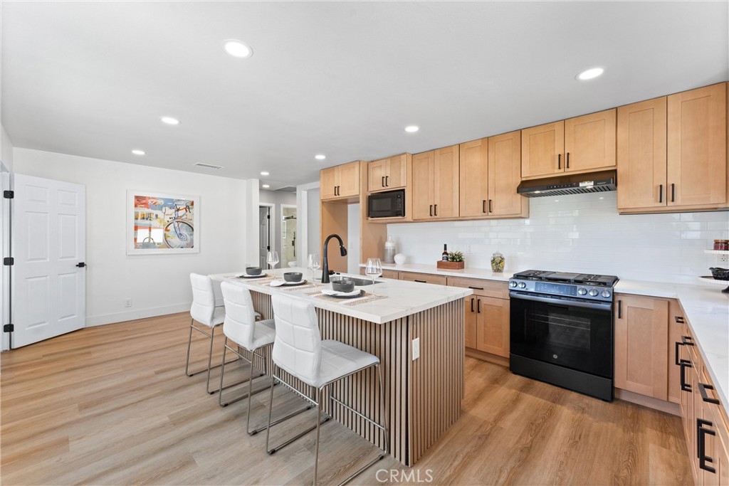 8039 4th Street Downey, CA 90241 - Photo 4 of 26 a kitchen with stainless steel appliances granite countertop a stove top oven a sink dishwasher and white cabinets with wooden floor
