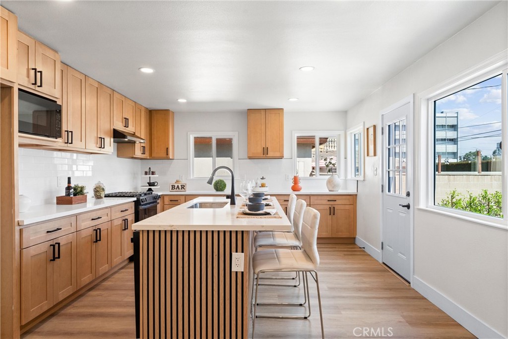 8039 4th Street Downey, CA 90241 - Photo 6 of 26 a kitchen with stainless steel appliances granite countertop a stove top oven a sink dishwasher and a refrigerator with wooden cabinets
