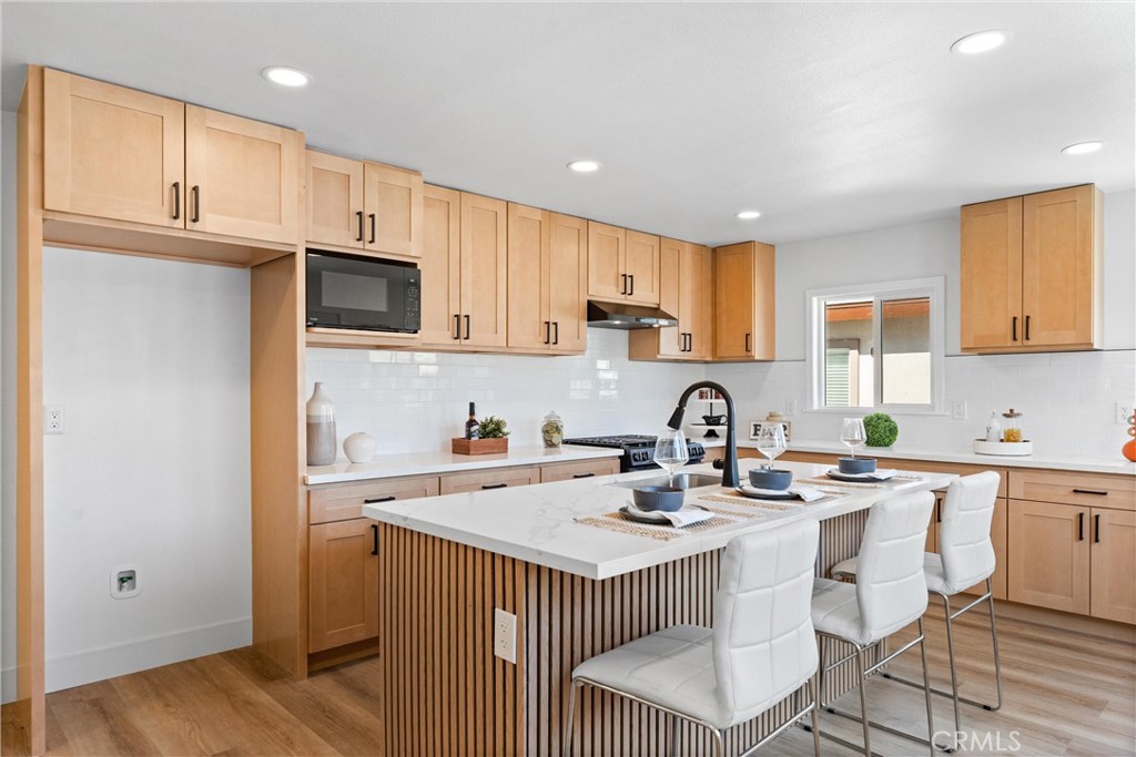 8039 4th Street Downey, CA 90241 - Photo 7 of 26 a kitchen with stainless steel appliances granite countertop a sink a stove a refrigerator cabinets and a dining table with wooden floor
