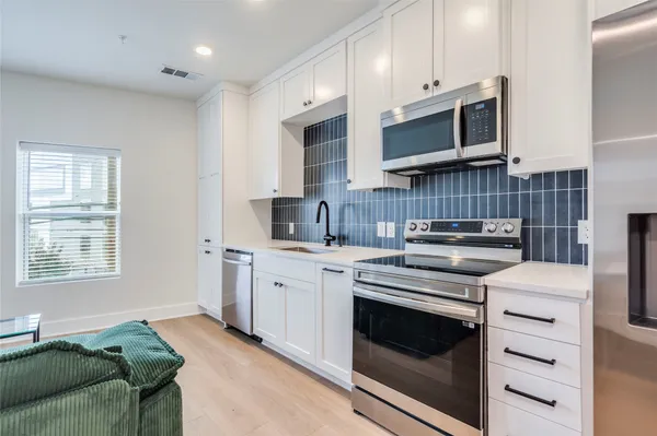 a kitchen with stainless steel appliances white cabinets and a stove top oven