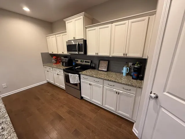 a kitchen with stainless steel appliances a stove a sink and white cabinets