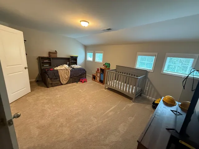 a bedroom with a bed and a flat tv screen on the dresser