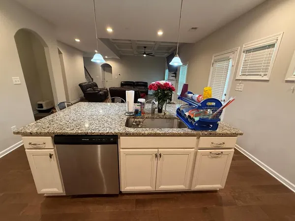 a kitchen with granite countertop a sink cabinets and wooden floor