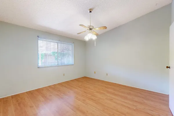 a view of an empty room with chandelier fan and wooden floor