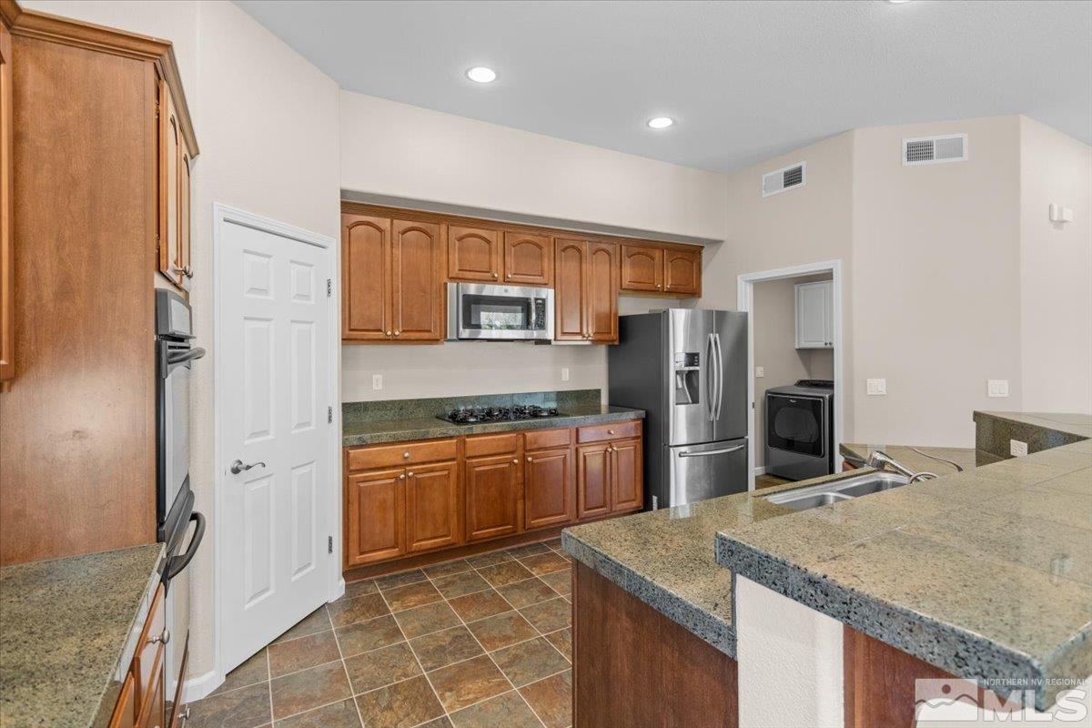 10560 Dillingham Drive Reno, NV 89521 - Photo 15 of 40 a kitchen with stainless steel appliances granite countertop a sink stove and refrigerator