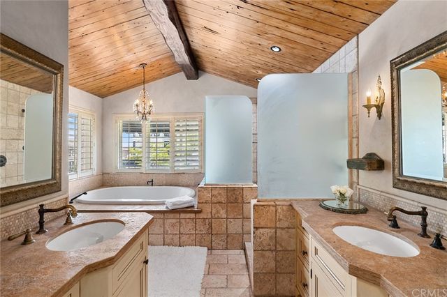 a bathroom with a granite countertop double vanity sink a mirror and a bathtub