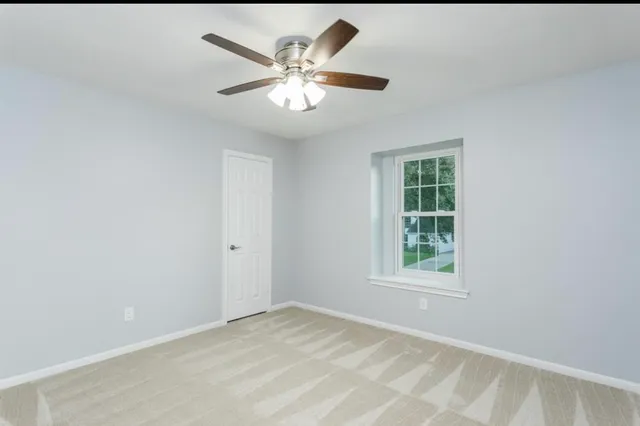 an empty room with windows and fan