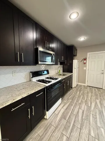 a large kitchen with stainless steel appliances granite countertop a stove a sink and a refrigerator
