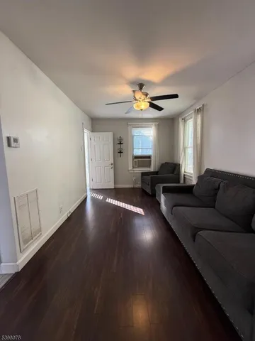 a living room with couches and potted plants with wooden floor
