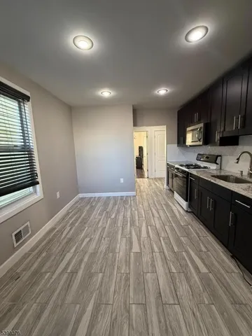 a large kitchen with stainless steel appliances granite countertop a stove a sink dishwasher and a microwave oven on the wooden floor