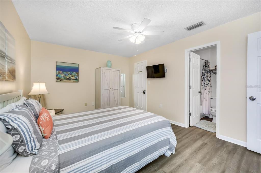 260 Medallion Boulevard, Unit F Madeira Beach, FL 33708 - Photo 12 of 29 a bedroom with a large bed and a chandelier