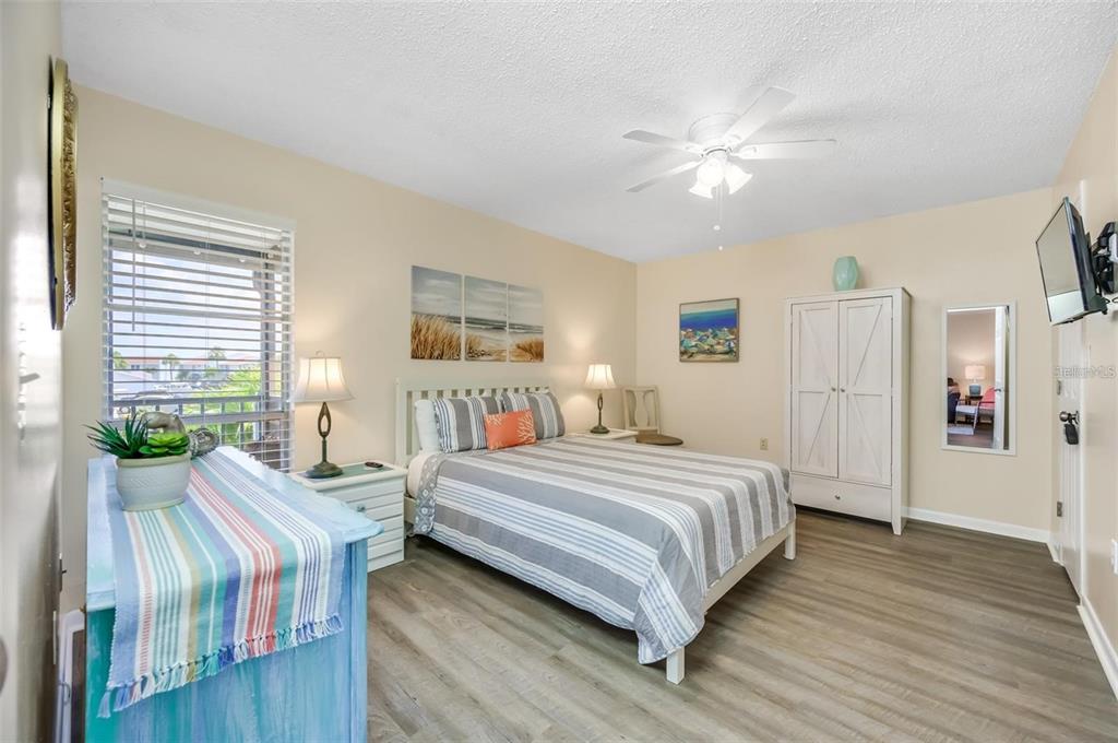 260 Medallion Boulevard, Unit F Madeira Beach, FL 33708 - Photo 14 of 29 a bedroom with a bed and a chandelier