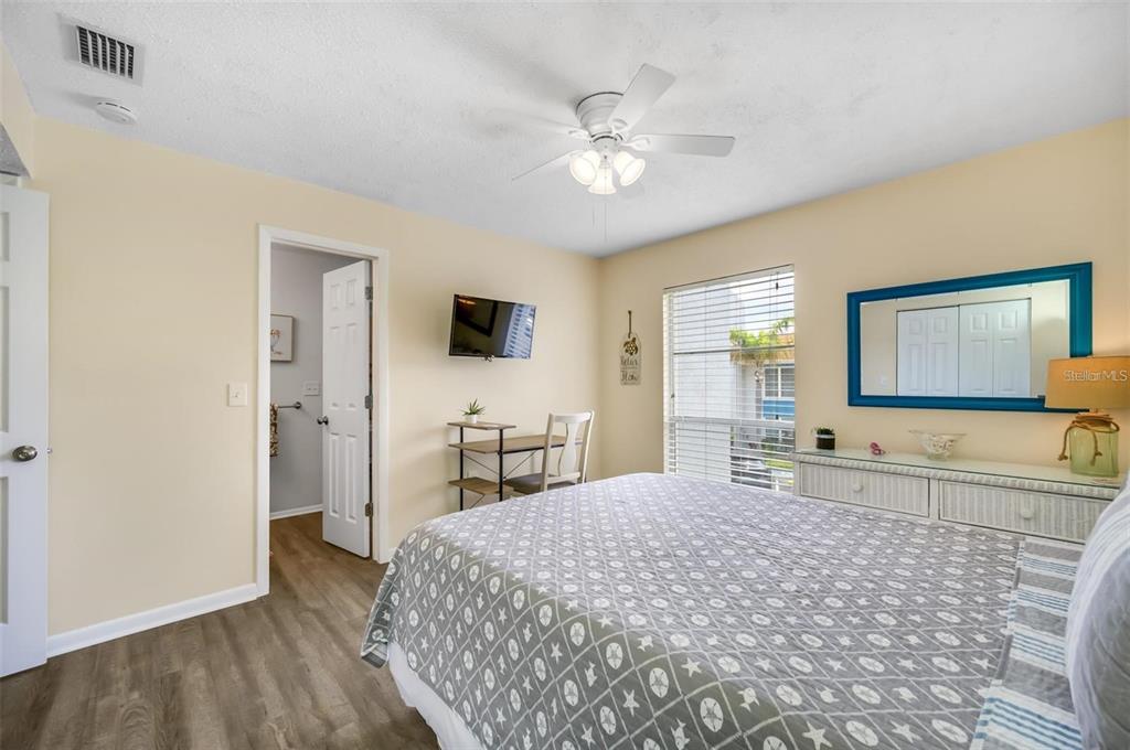 260 Medallion Boulevard, Unit F Madeira Beach, FL 33708 - Photo 16 of 29 a spacious bedroom with a large bed and a chandelier