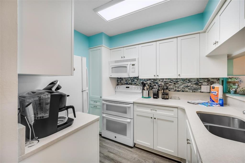 260 Medallion Boulevard, Unit F Madeira Beach, FL 33708 - Photo 9 of 29 a kitchen with white cabinets and appliances