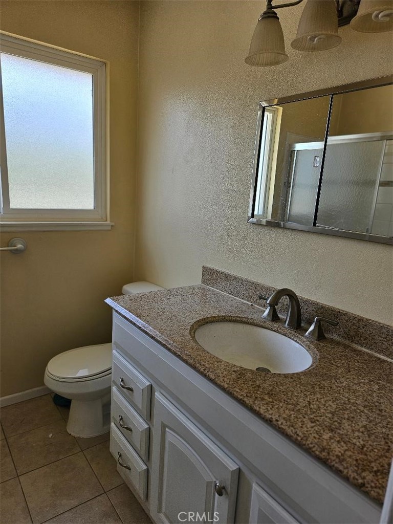 12627 Longleaf Drive La Mirada, CA 90638 - Photo 9 of 19 a bathroom with a granite countertop toilet a sink and mirror
