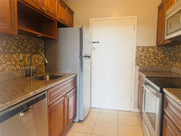 a kitchen with granite countertop a sink and a refrigerator