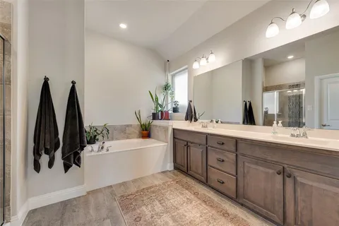 a spacious bathroom with a double vanity sink a mirror and a bathtub
