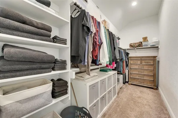 a view of walk in closet with clothes and shoes