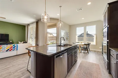 a kitchen with counter top space a sink appliances and living room view