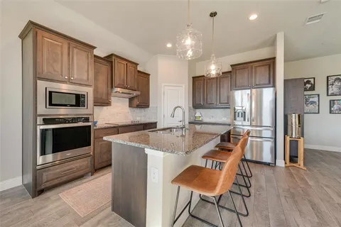 a kitchen with stainless steel appliances granite countertop a refrigerator stove microwave and white cabinets