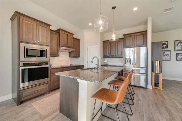 a kitchen with stainless steel appliances granite countertop a refrigerator stove microwave and white cabinets
