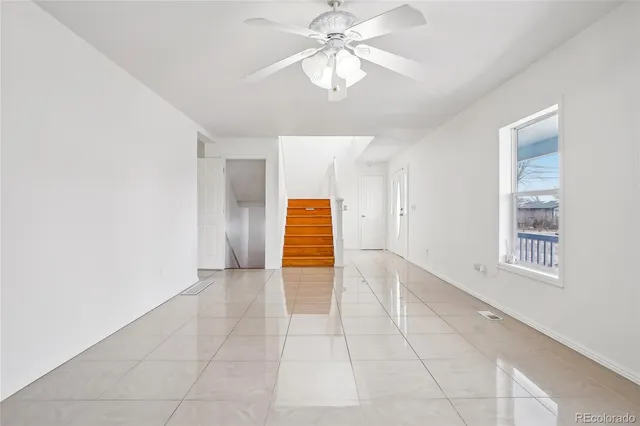 a view of an empty room with window and chandelier fan