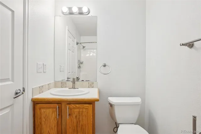a bathroom with a granite countertop toilet a sink and a mirror