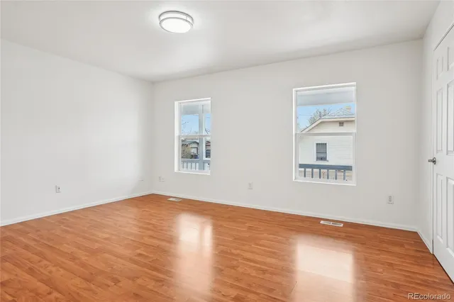 an empty room with wooden floor and windows