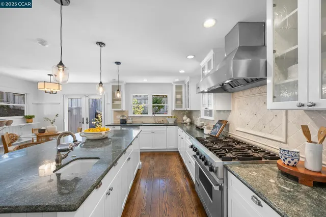 a kitchen with granite countertop a stove a sink a counter space and stainless steel appliances
