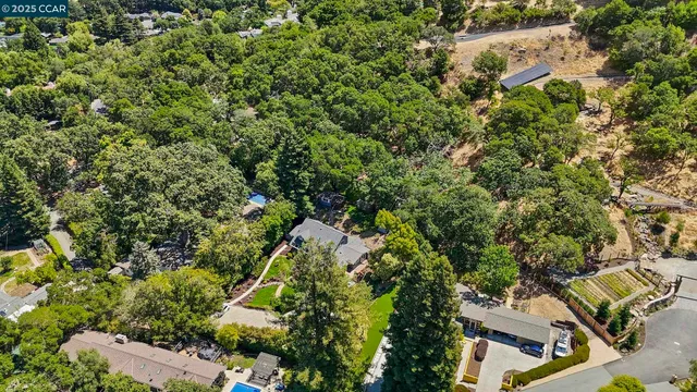 an aerial view of residential house with outdoor space and trees all around