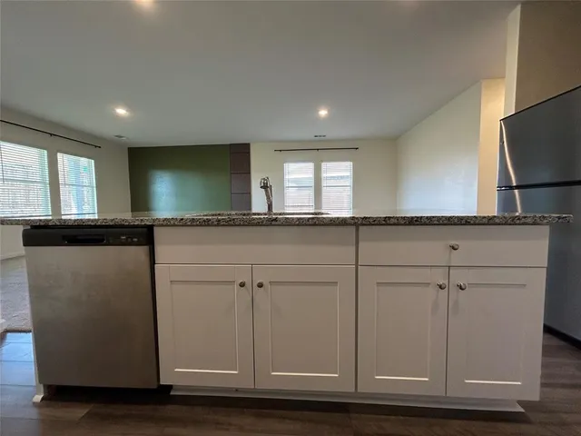 a kitchen with stainless steel appliances granite countertop a sink a stove and a refrigerator