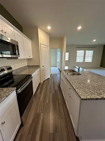 a kitchen with stainless steel appliances granite countertop white cabinets and a stove top oven