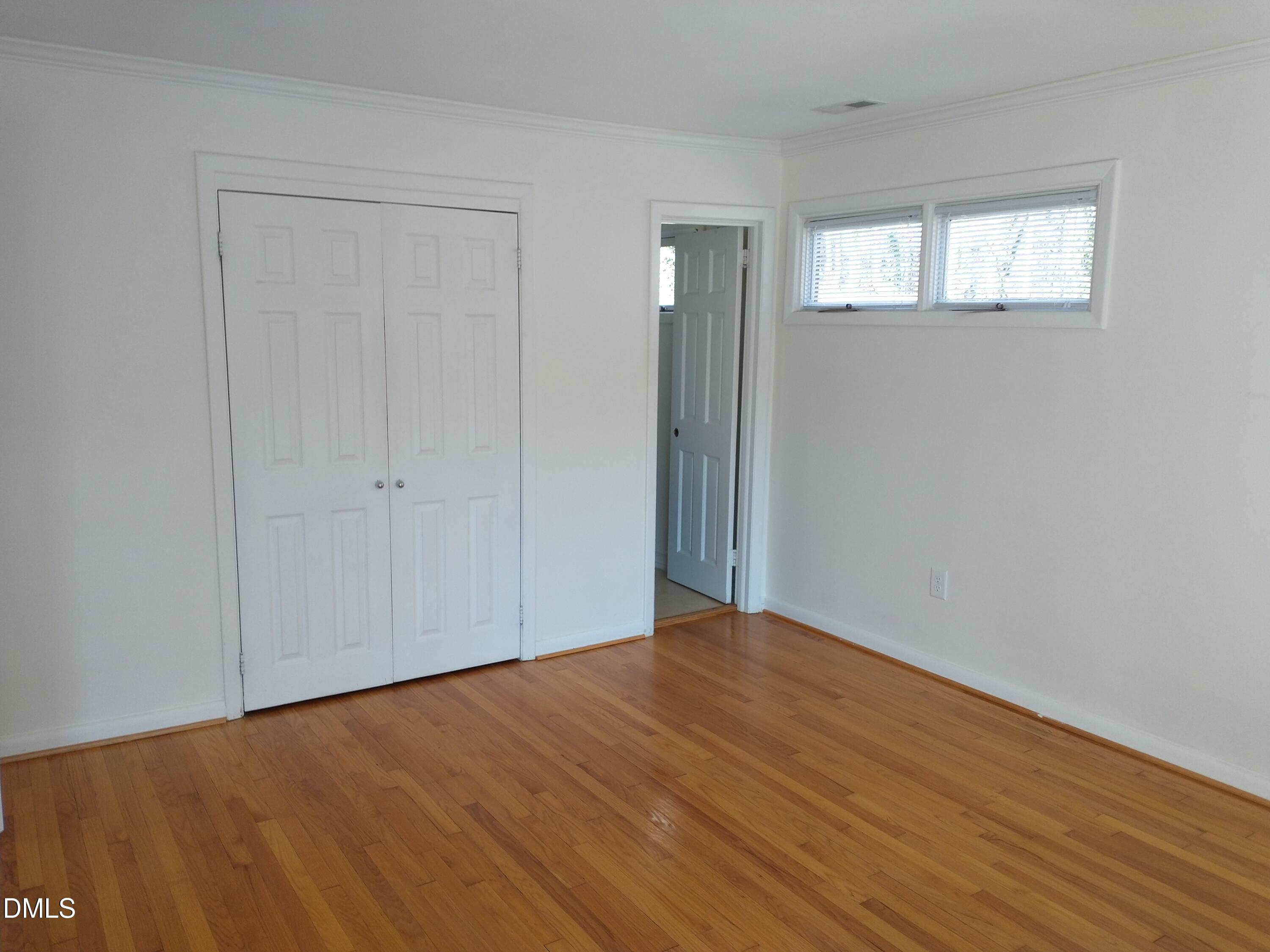 1302 Lorimer Road Raleigh, NC 27606 - Photo 10 of 23 a view of an empty room with wooden floor and a window