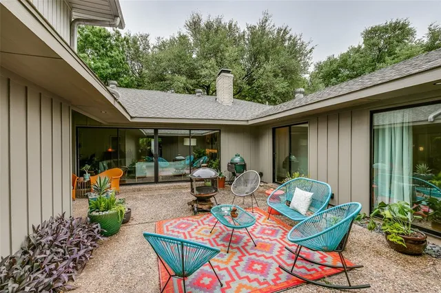 a view of a patio with table and chairs potted plants and floor to ceiling window