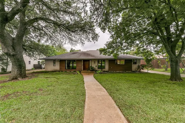 a front view of a house with a garden and trees