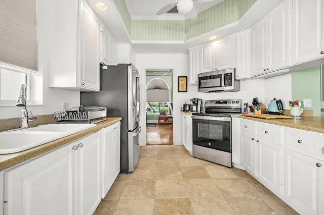 a kitchen with stainless steel appliances granite countertop white cabinets a sink a stove a refrigerator and island