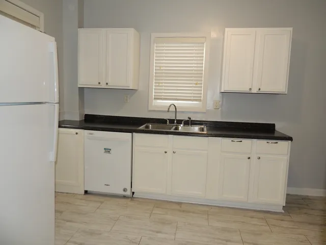 a kitchen with granite countertop white cabinets white appliances and a sink