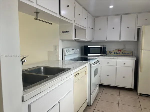a kitchen with white cabinets and white appliances