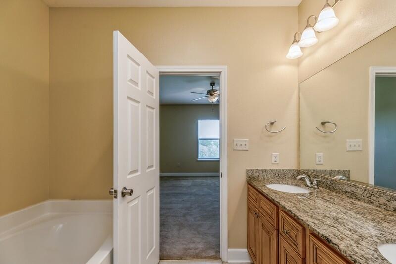 513 Arbor Lake Drive, Unit 513 Crestview, FL 32536 - Photo 24 of 37 a bathroom with a granite countertop sink a mirror and a bathtub